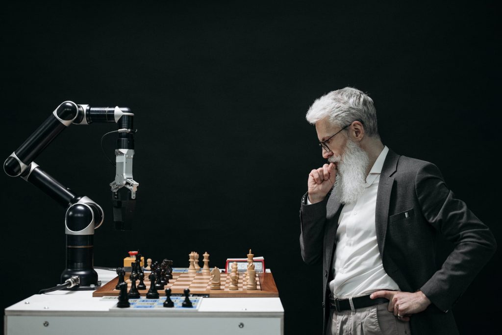 Mann spielt Schach mit Roboterarm